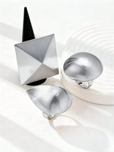 Three metallic jewelry pieces on a white background
