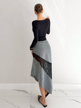 Woman wearing a black top and a checkered skirt with lace panels on a white background