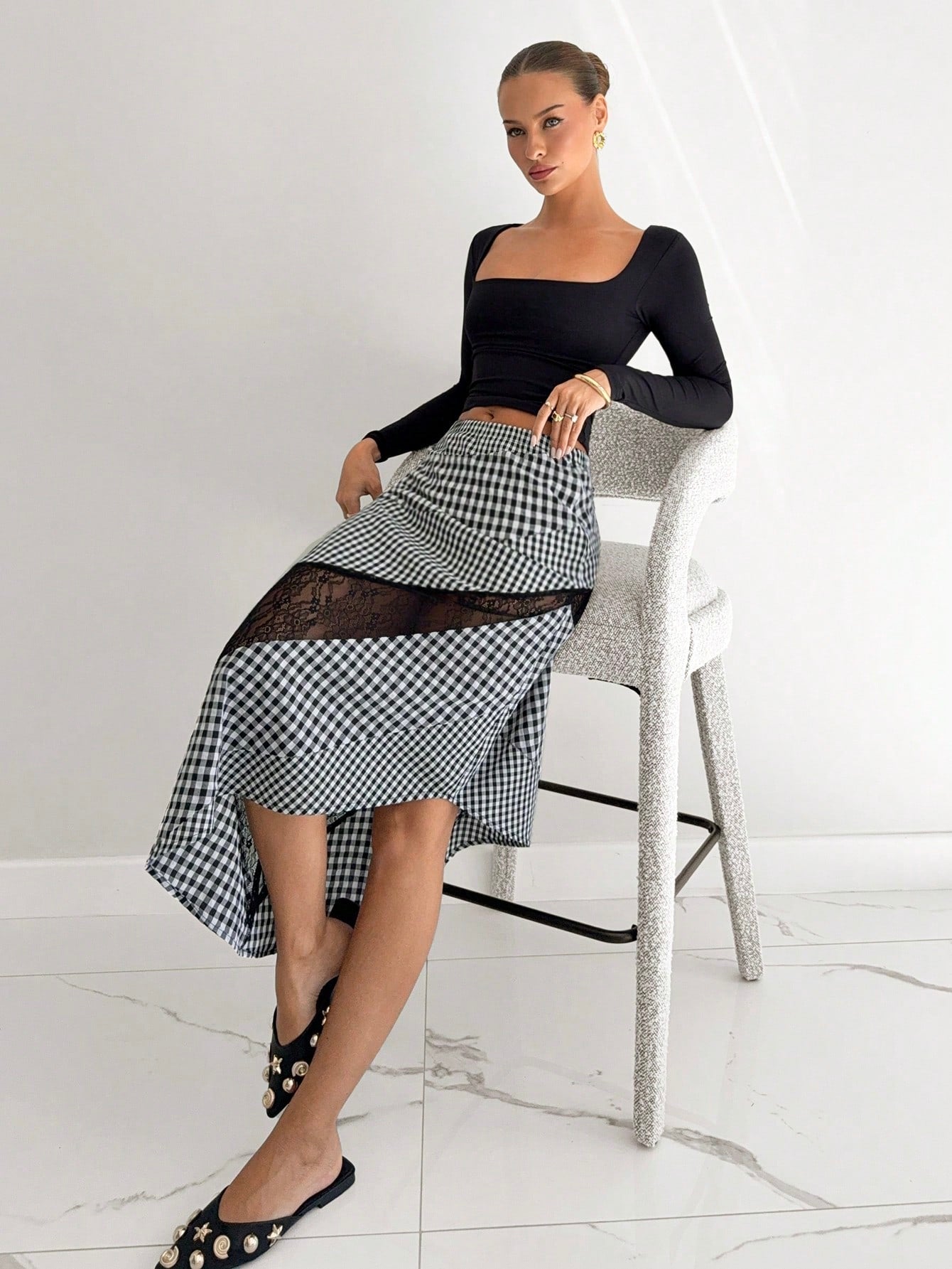Woman wearing a black top and checkered skirt in a minimalistic setting