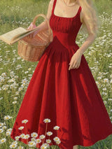 Woman in a red dress holding a basket and book in a field of flowers