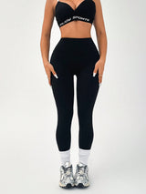 Person wearing a black sports bra and leggings set on a white background