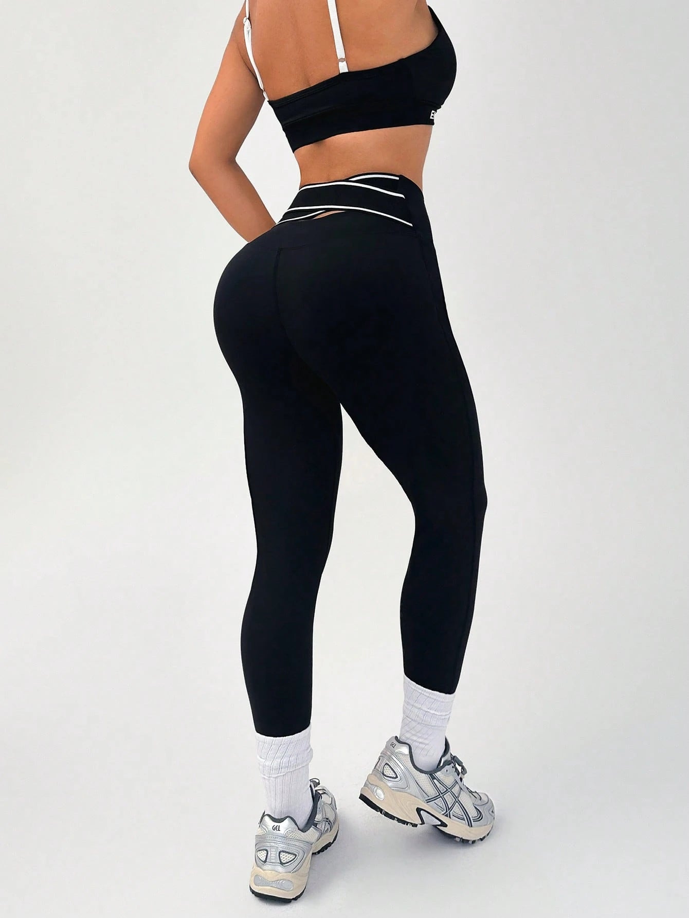 Person wearing black leggings and a black sports bra on a white background