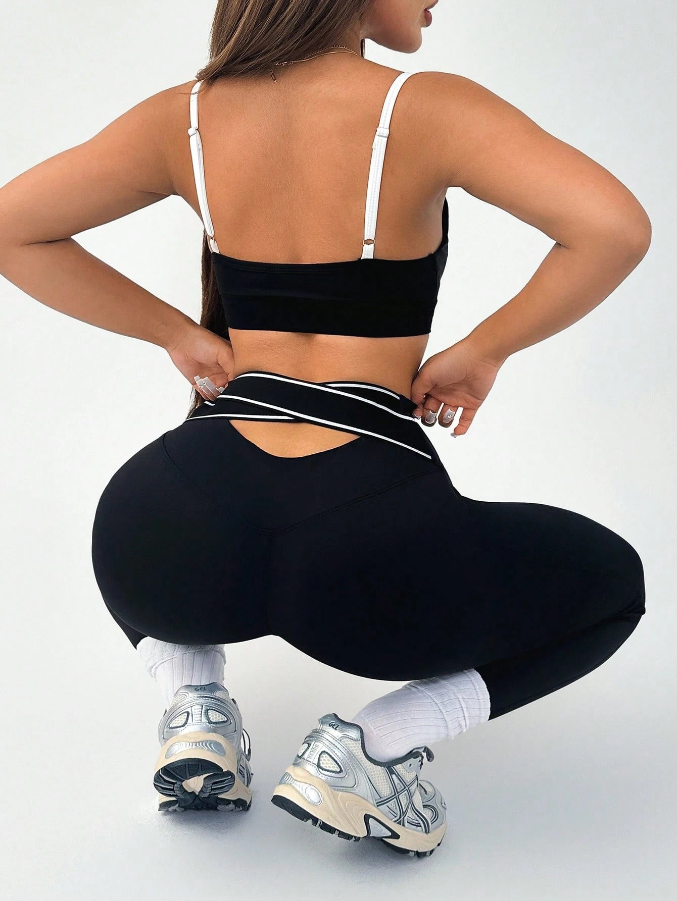 Person wearing black athletic leggings and sports bra on a white background