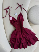 Maroon ruffled dress on a white surface with a light gray ball in the background