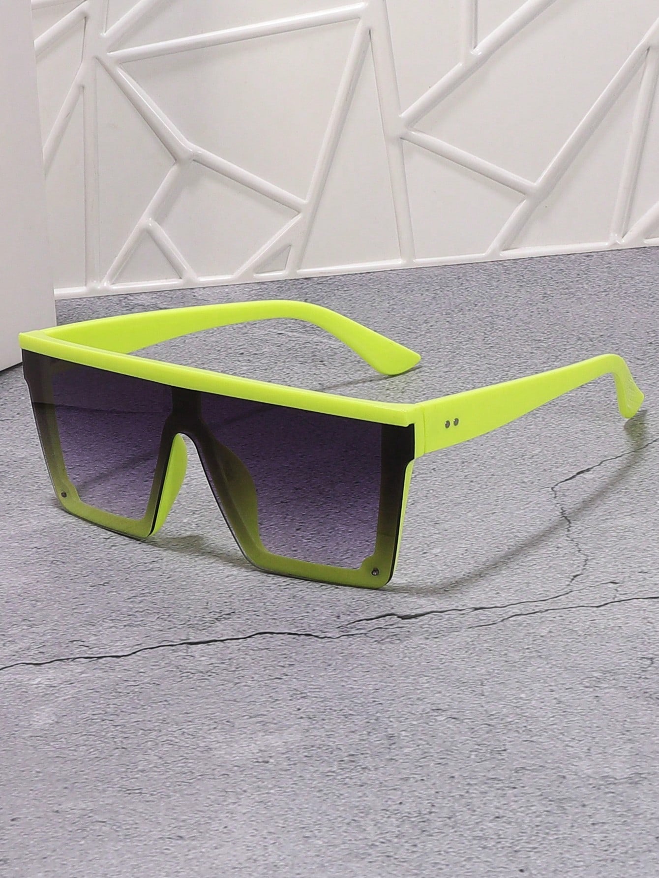 Sunglasses with a bright green frame on a gray surface