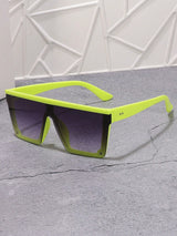 Sunglasses with a bright green frame on a gray surface