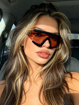 Woman wearing orange-tinted sunglasses inside a car