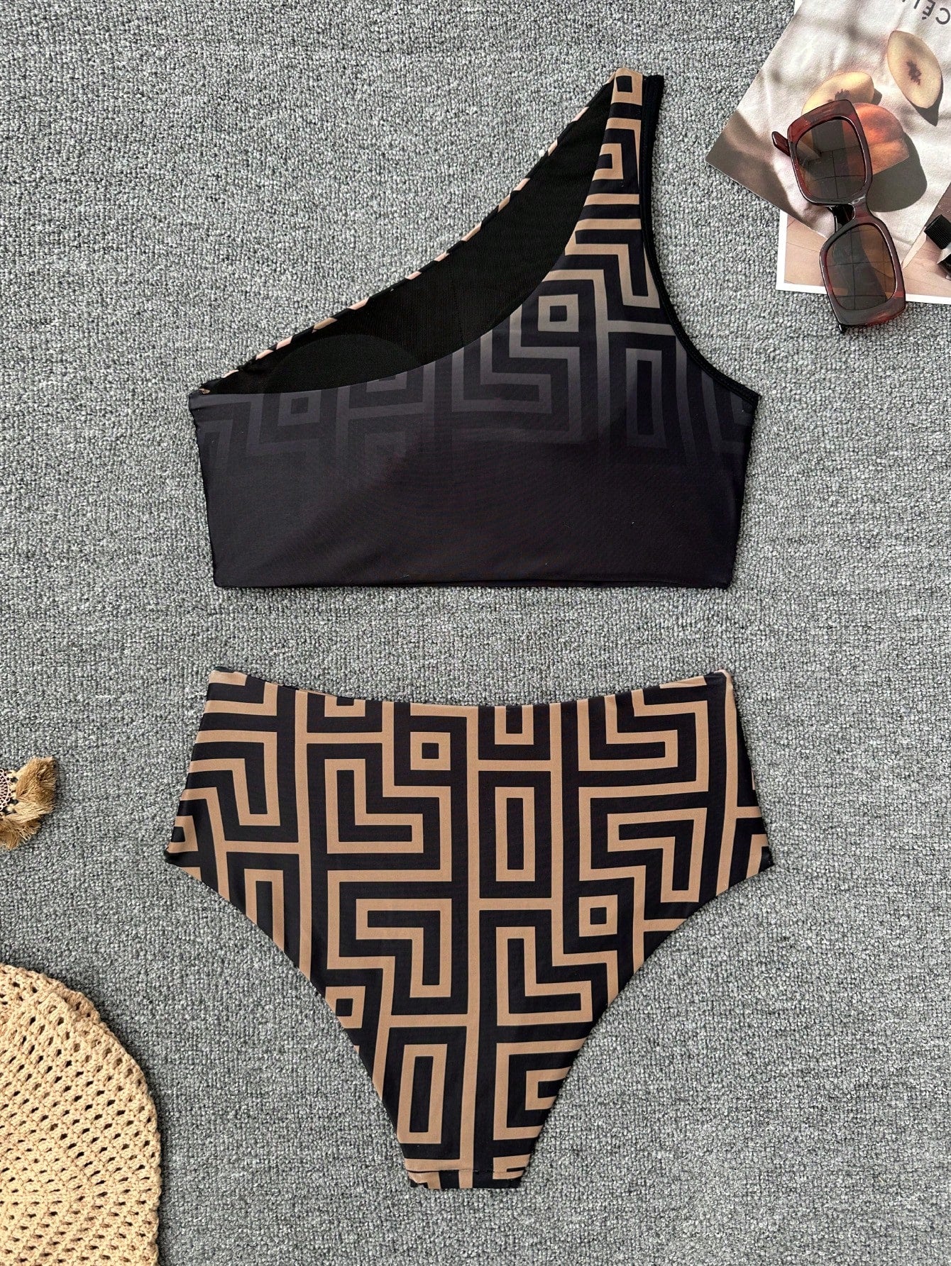 Black and patterned bikini set on a textured surface with sunglasses and a hat.