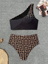 Black and patterned bikini set on a textured surface with sunglasses and a hat.