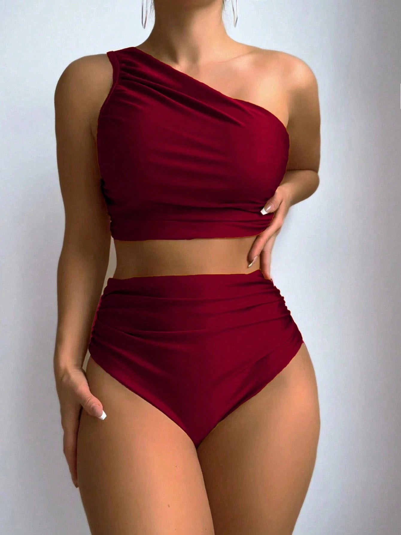 Red one-shoulder top and high-waisted bikini bottom set on a plain background