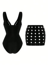 Black swimsuit with cut-out design and matching skirt on a white background