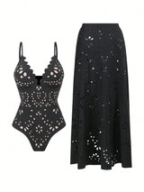 A black eyelet swimwear set featuring a one-piece swimsuit with scalloped cups and a matching high-waisted midi skirt, both decorated with floral cutout patterns, shown on a plain white background.