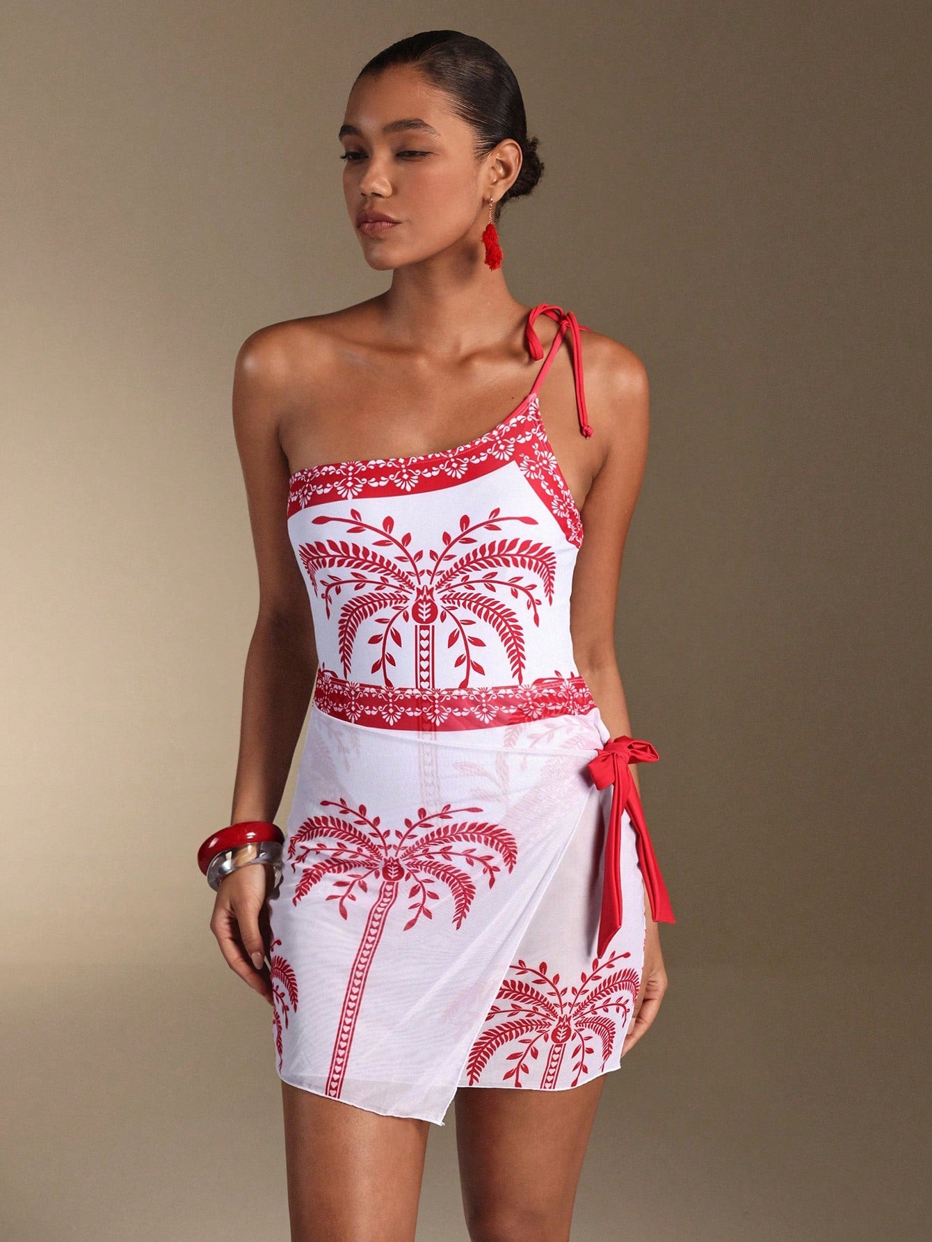 Woman wearing a white dress with red embroidery and a red strap on a beige background