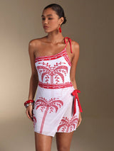 Woman wearing a white dress with red embroidery and a red strap on a beige background