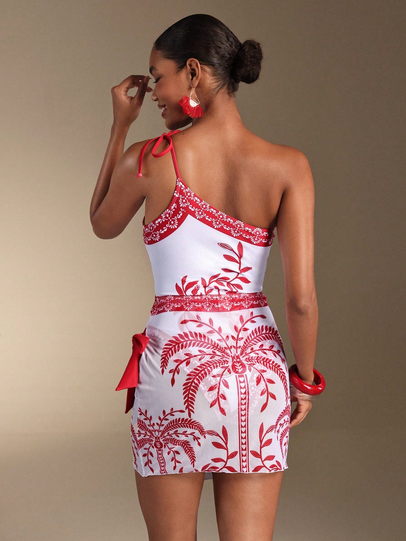 Woman wearing a white dress with red floral patterns against a beige background