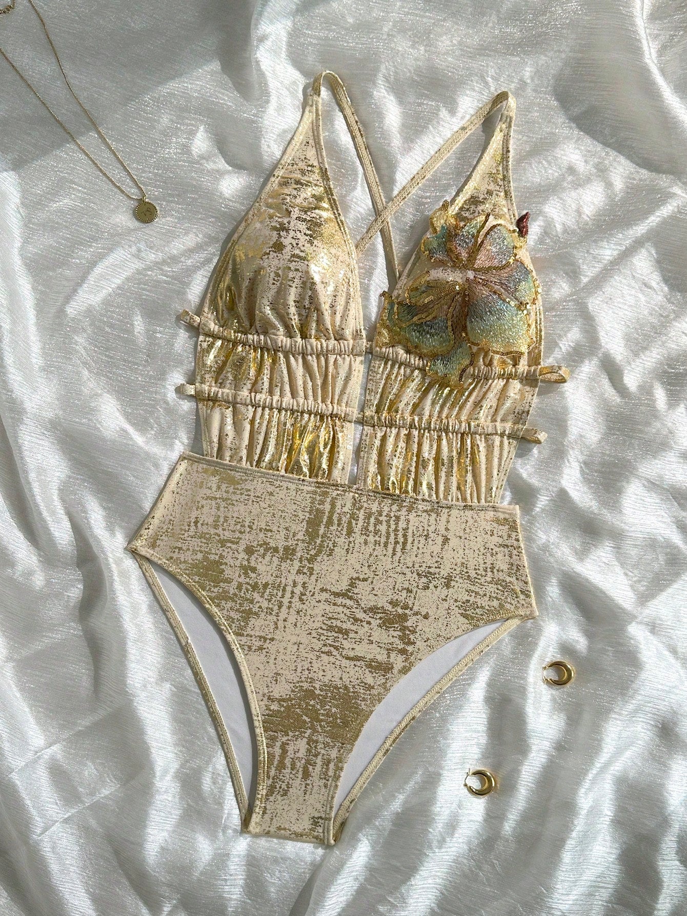 Gold swimsuit set on a textured white surface