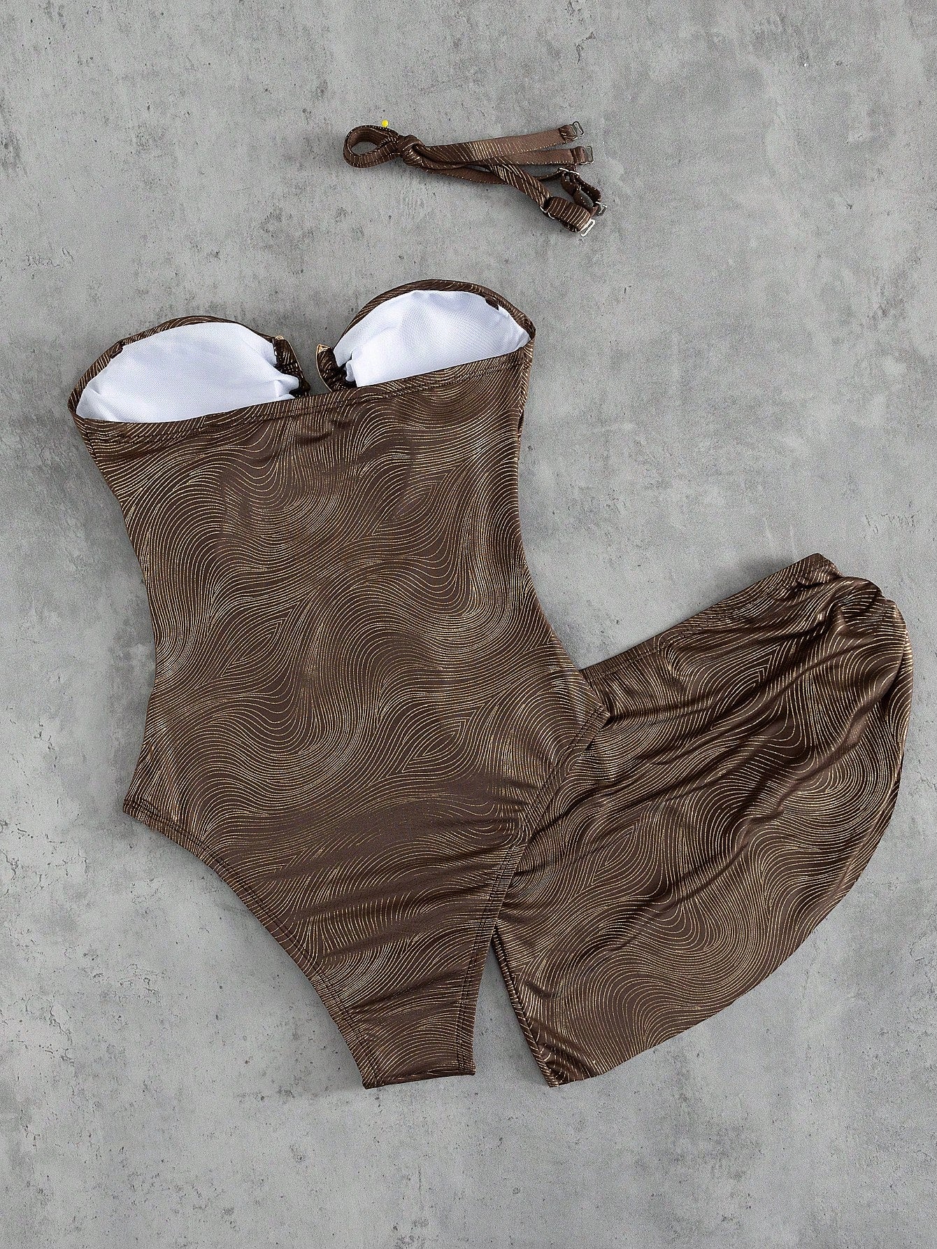 Brown swimsuit with white lining on a gray concrete surface