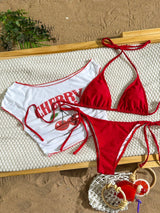 Red and white bikini set on a textured surface with a plant in the background