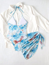 Blue and white floral swimsuit with a white long-sleeve top on a light gray background