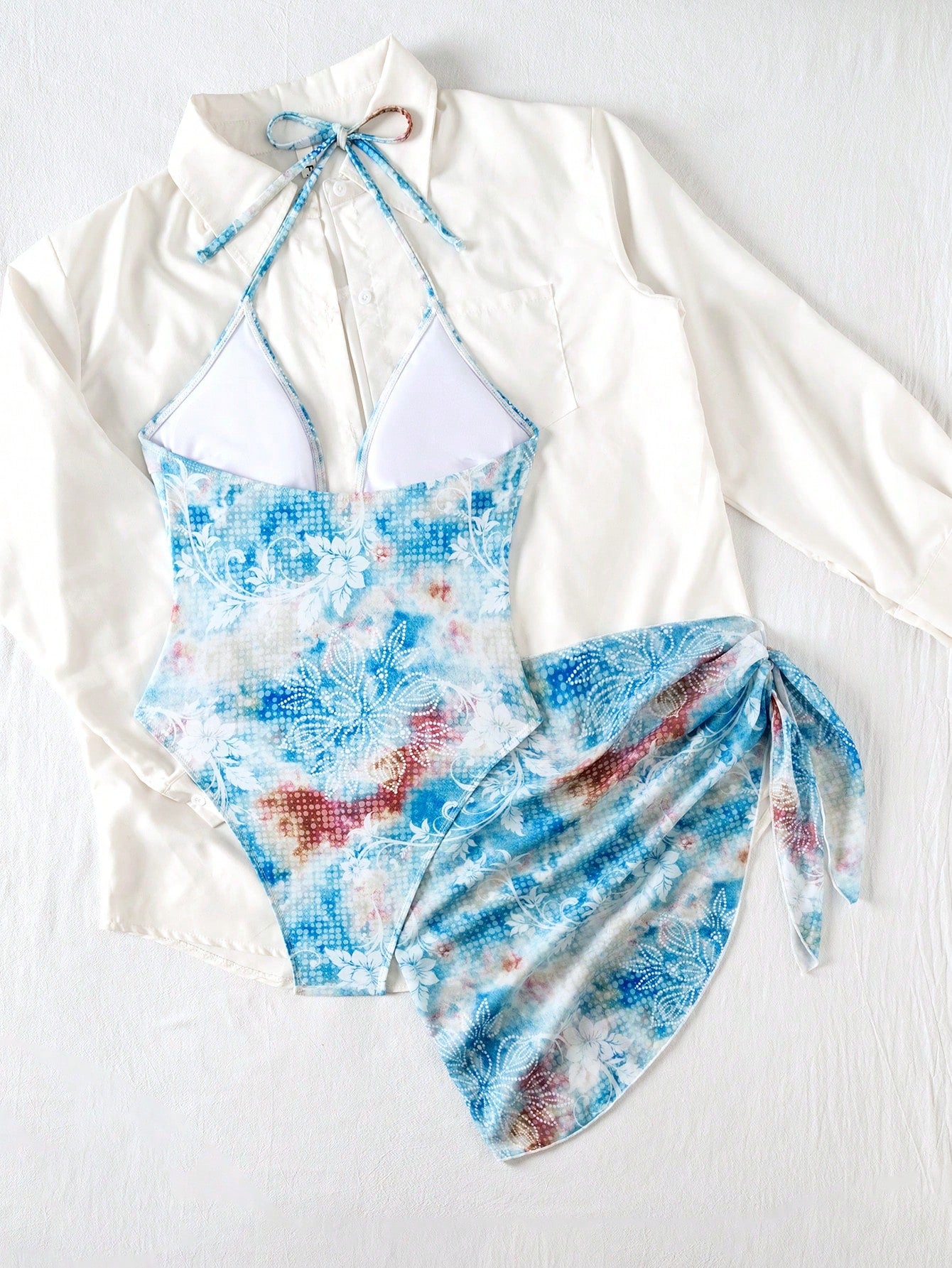 Blue and white floral swimsuit with a white long-sleeve top on a light gray background