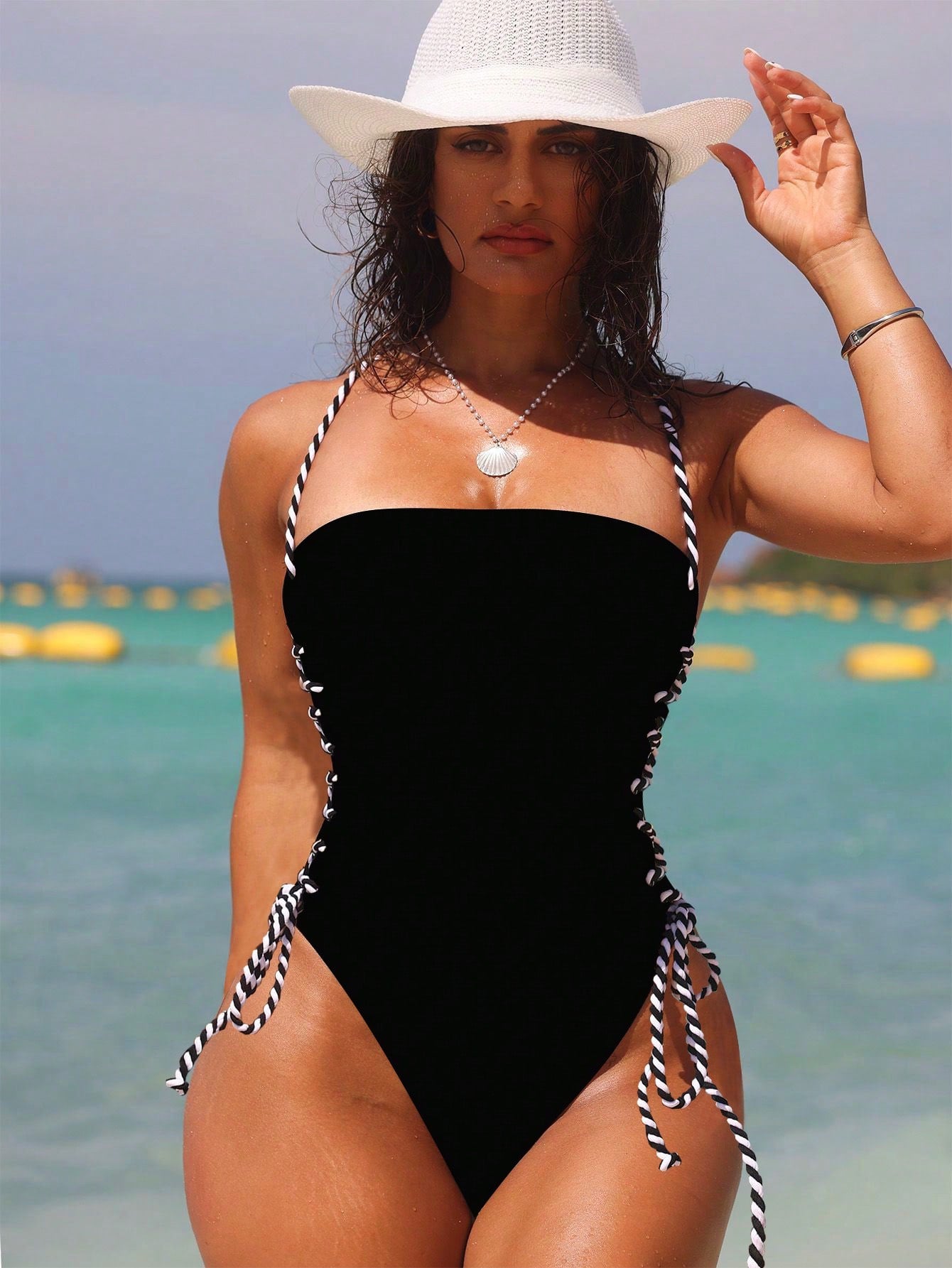 Woman in a black swimsuit with white hat on a beach