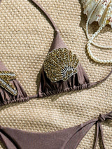 Brown bikini set with embellishments on a textured surface