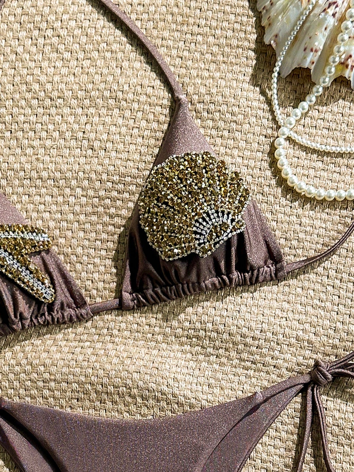 Brown bikini set with embellishments on a textured surface