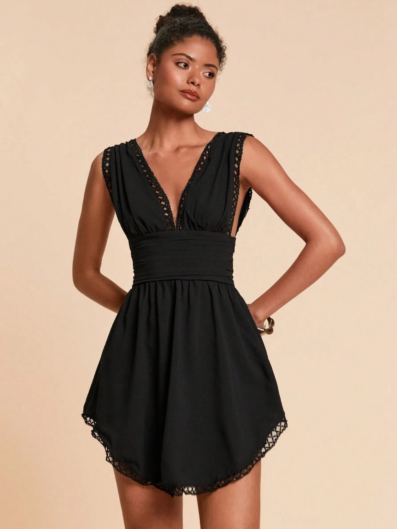 Woman wearing a black dress with lace details on a beige background