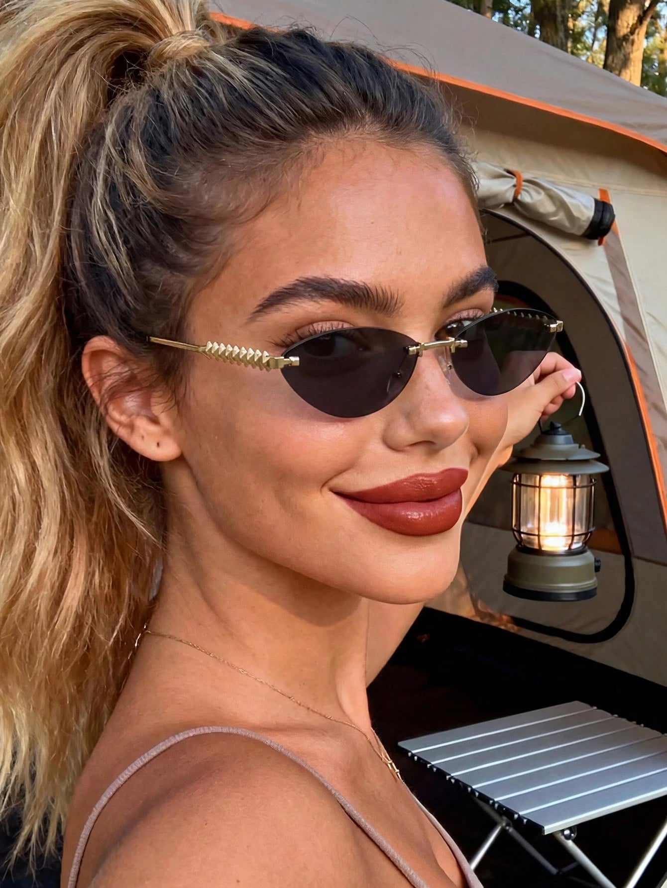 Woman wearing sunglasses with a camping scene in the background