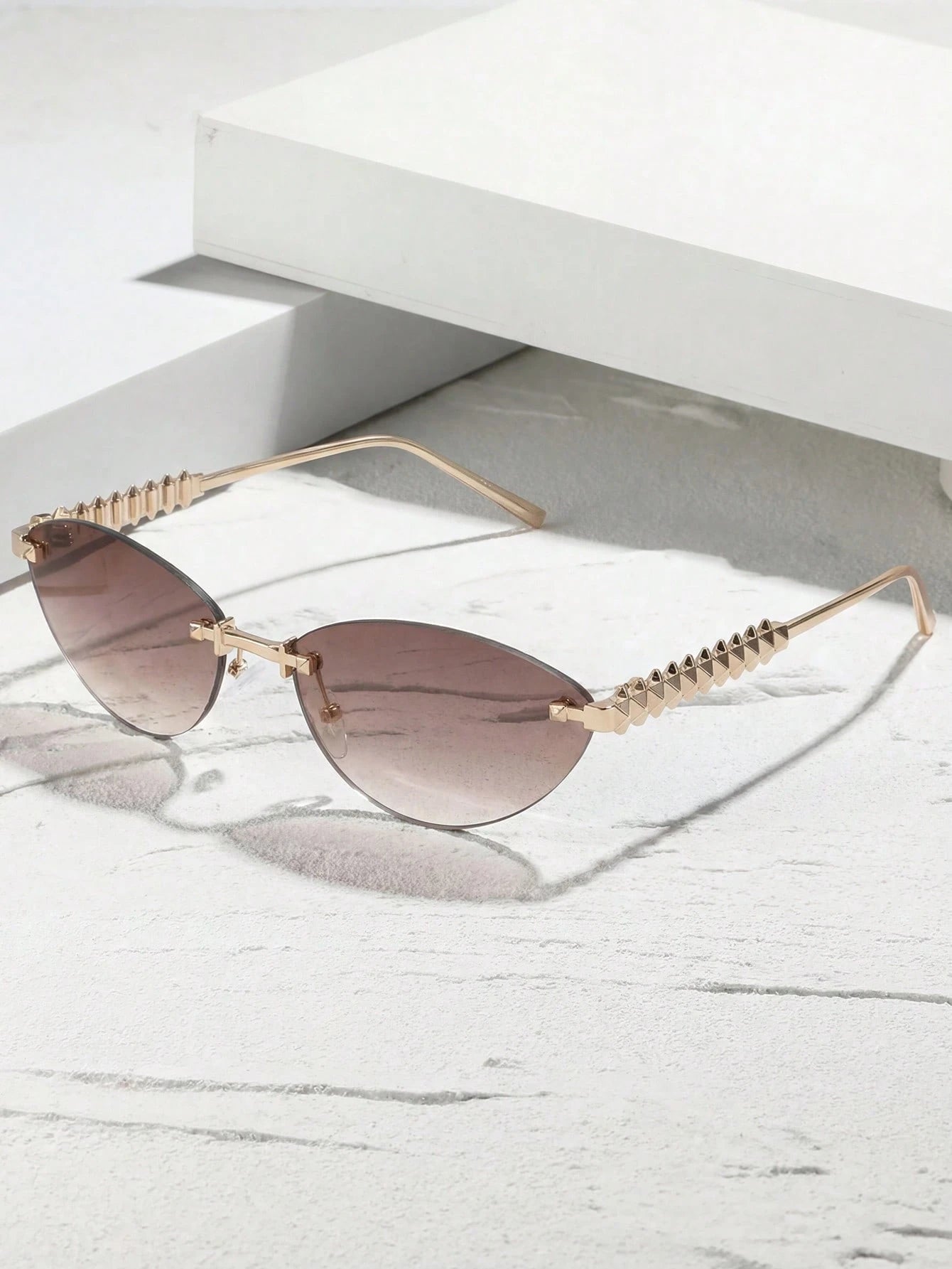 Gold-framed sunglasses with gradient lenses on a white surface