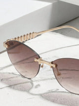 Sunglasses with gold frame and brown lenses on a marble surface