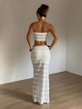 Woman wearing a white lace dress standing in a minimal room.