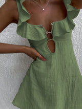 Green dress with ruffled details on a textured white background