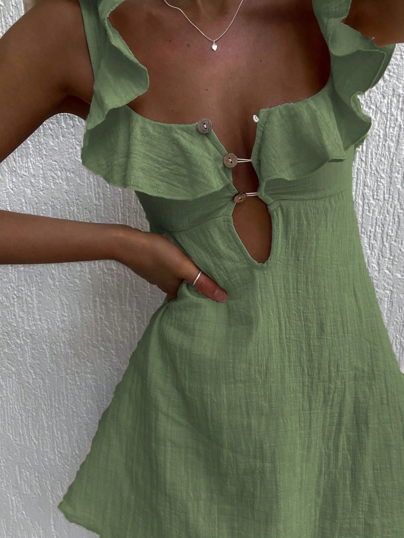 Green dress with ruffled details on a textured white background