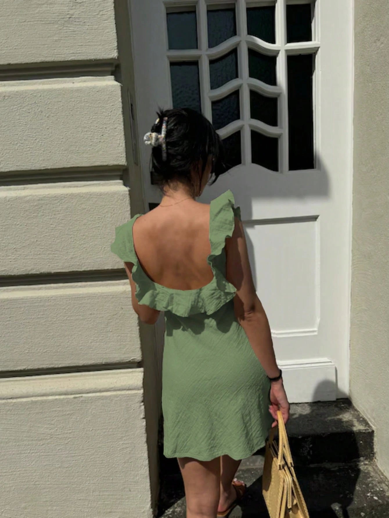 Person wearing a green dress standing in front of a white door.