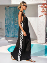 Woman wearing a black dress with white patterns by a poolside.