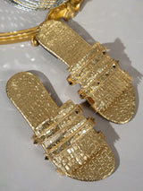 Pair of gold sandals with textured design on a light gray background