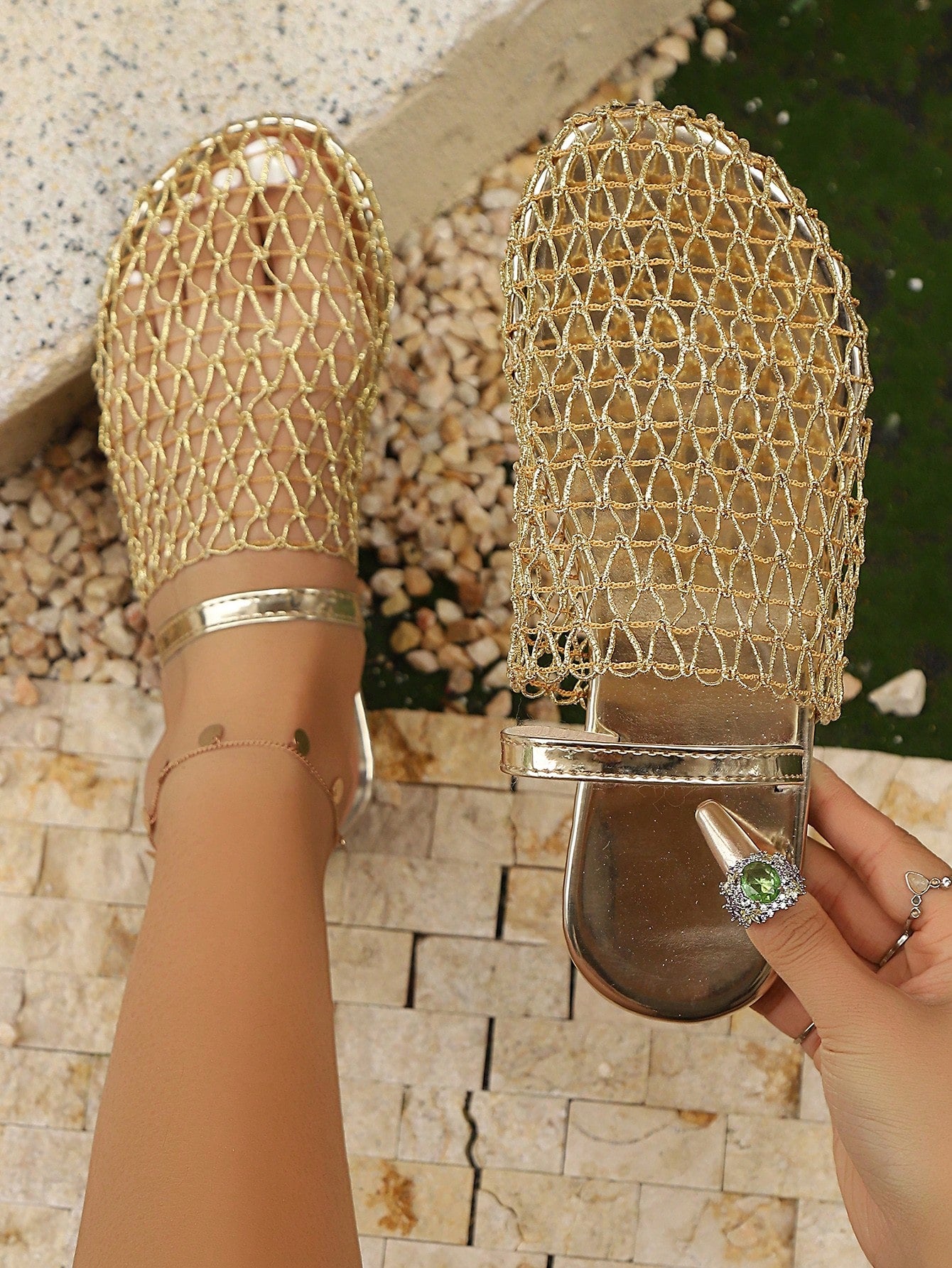 Gold mesh sandals being worn with a stone wall background