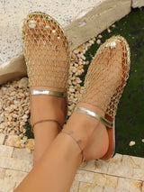 Gold mesh sandals worn by a person on a stone surface.
