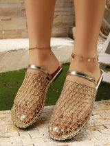 Gold mesh sandals worn by a person on a stone surface with grass in the background