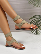 Pair of beige sandals worn by a person on a light background