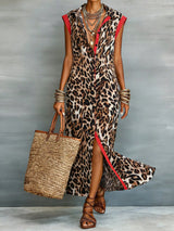 Woman wearing a leopard print dress with red accents, holding a straw bag against a gray background