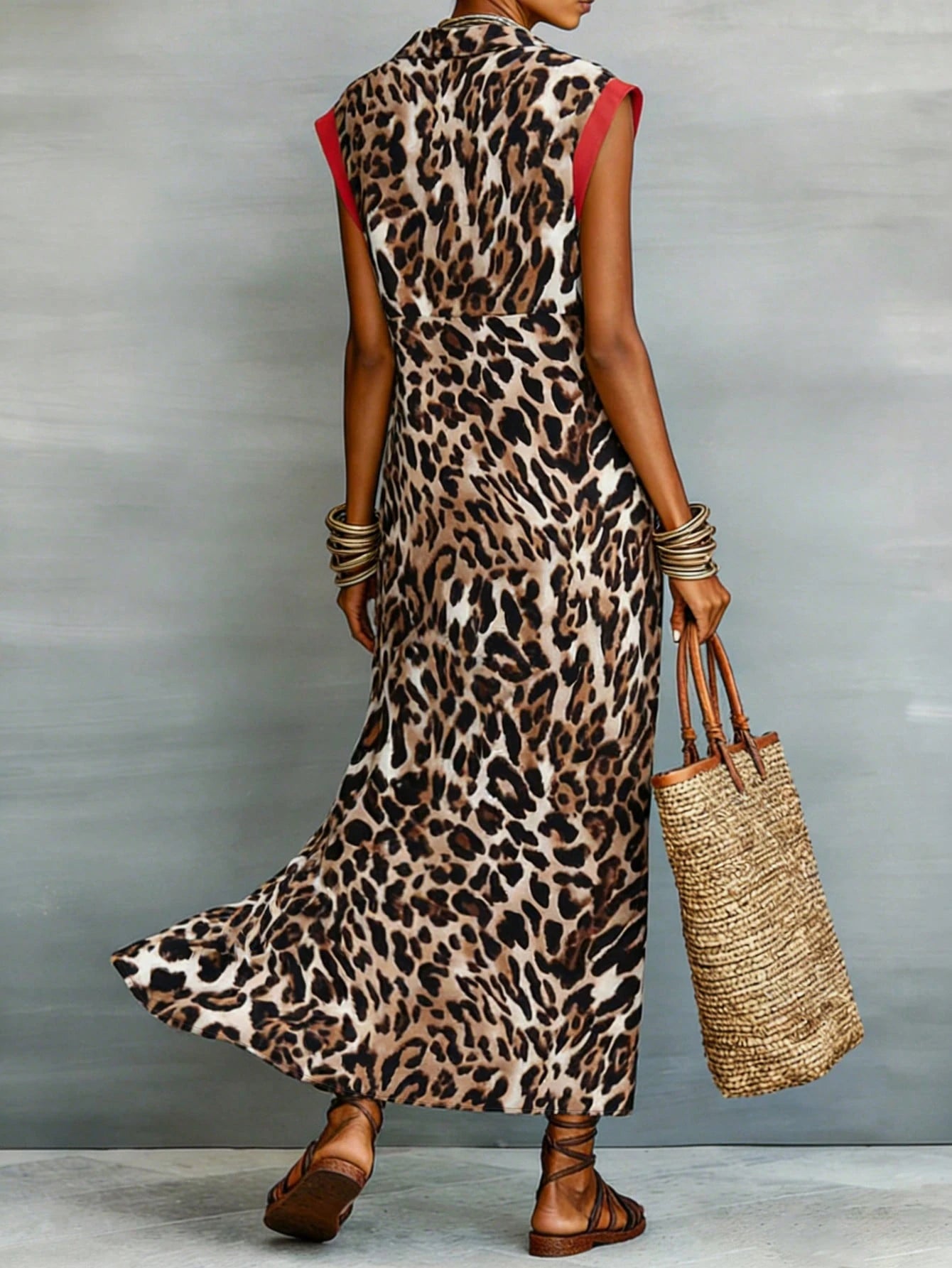 Person wearing a leopard print dress holding a straw bag against a gray background