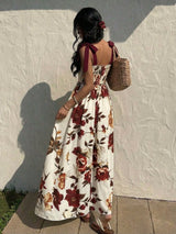 Woman in a floral dress standing against a textured wall.
