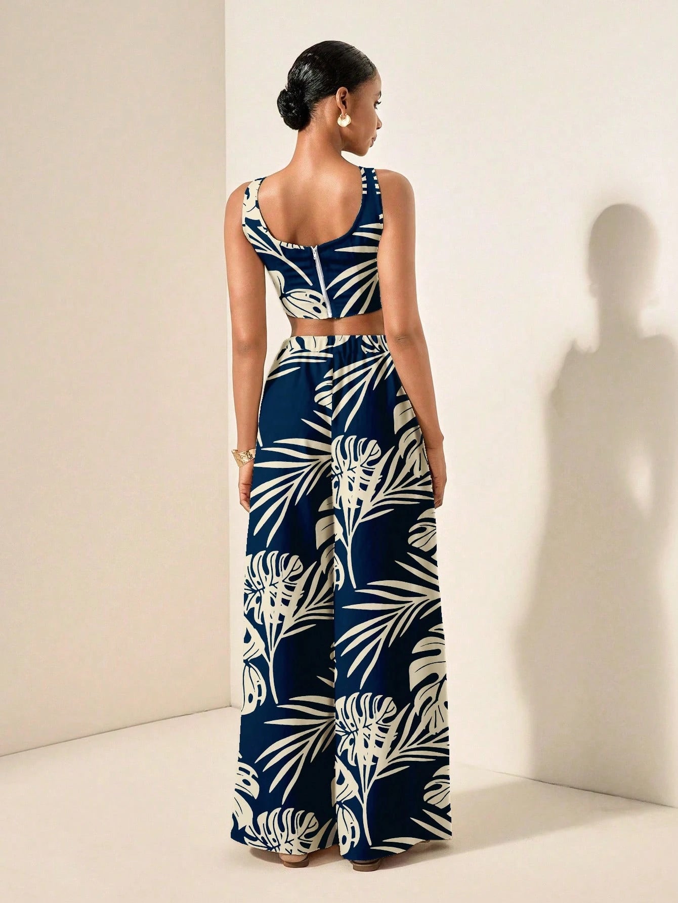 Woman wearing a navy blue and white leaf-patterned jumpsuit against a plain background